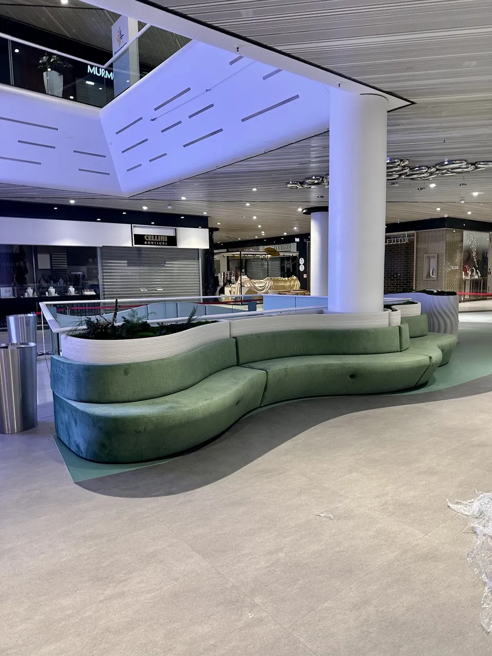 Curved green sofas around a printed concrete planter in the atrium